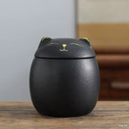 Black cat-shaped container on a wooden surface with a blurred background