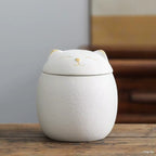White ceramic cat-shaped container on a wooden surface with a blurred background